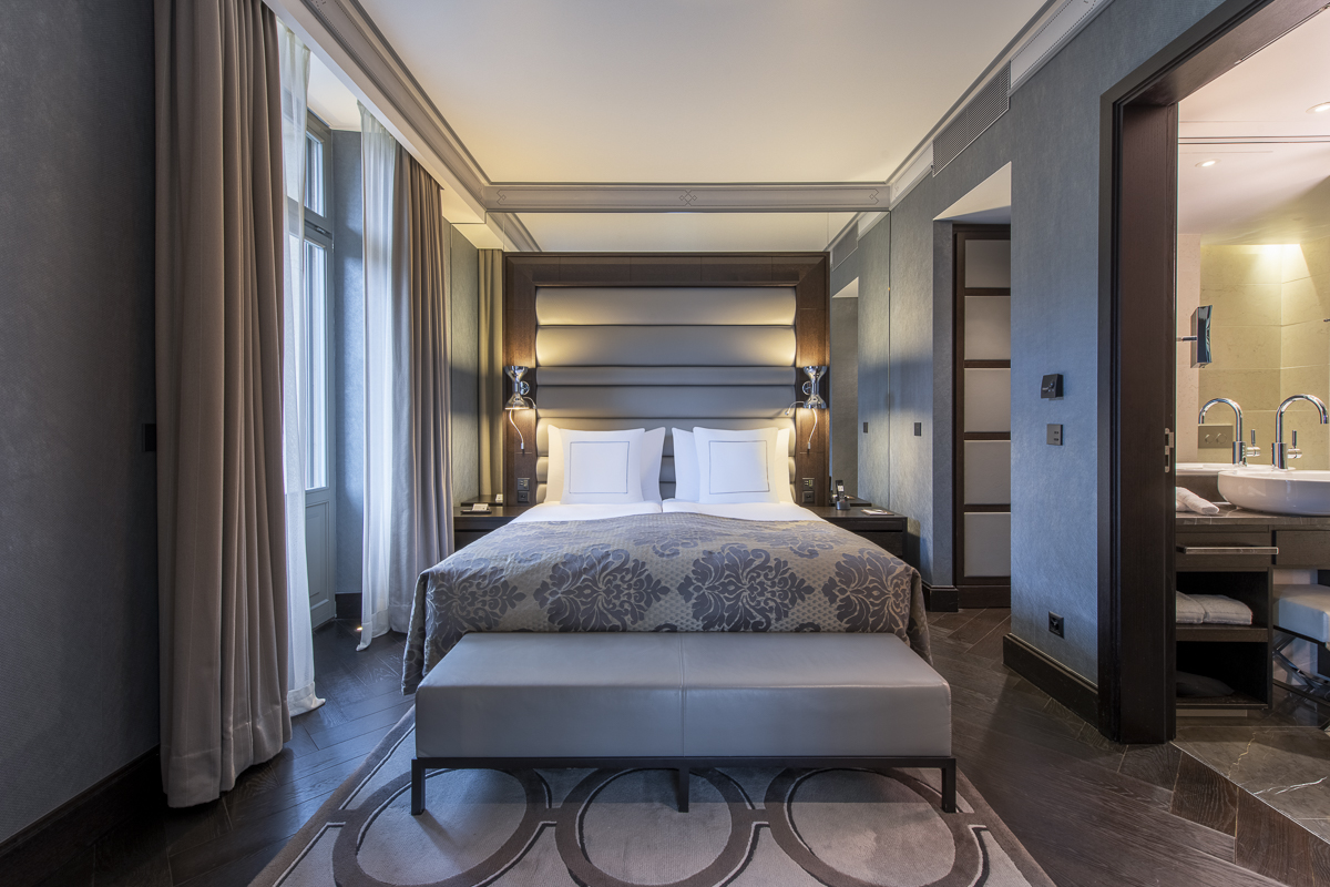 Elegant bedroom suite with cool blue and grey tones, tastefully inviting ambiance for hotel guests seeking comfort and style.