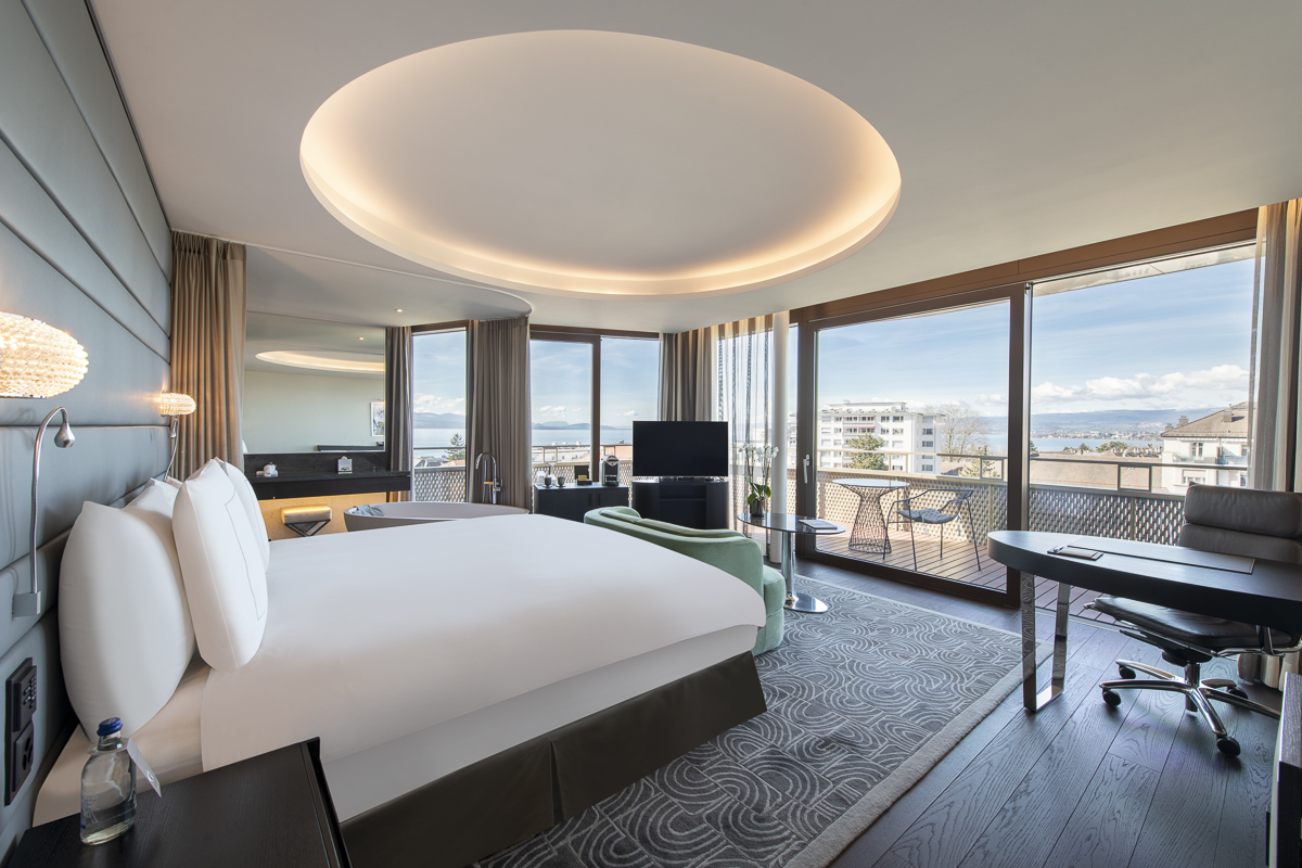 Elegant hotel room with ocean view, sophisticated design in soothing greys and earth tones, inviting relaxation and luxury.
