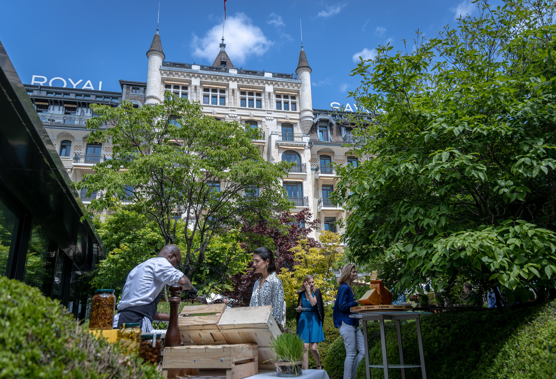 Lush garden event at a heritage hotel, featuring bustling staff and attendees, evokes a sense of vibrant community engagement in hospitality.