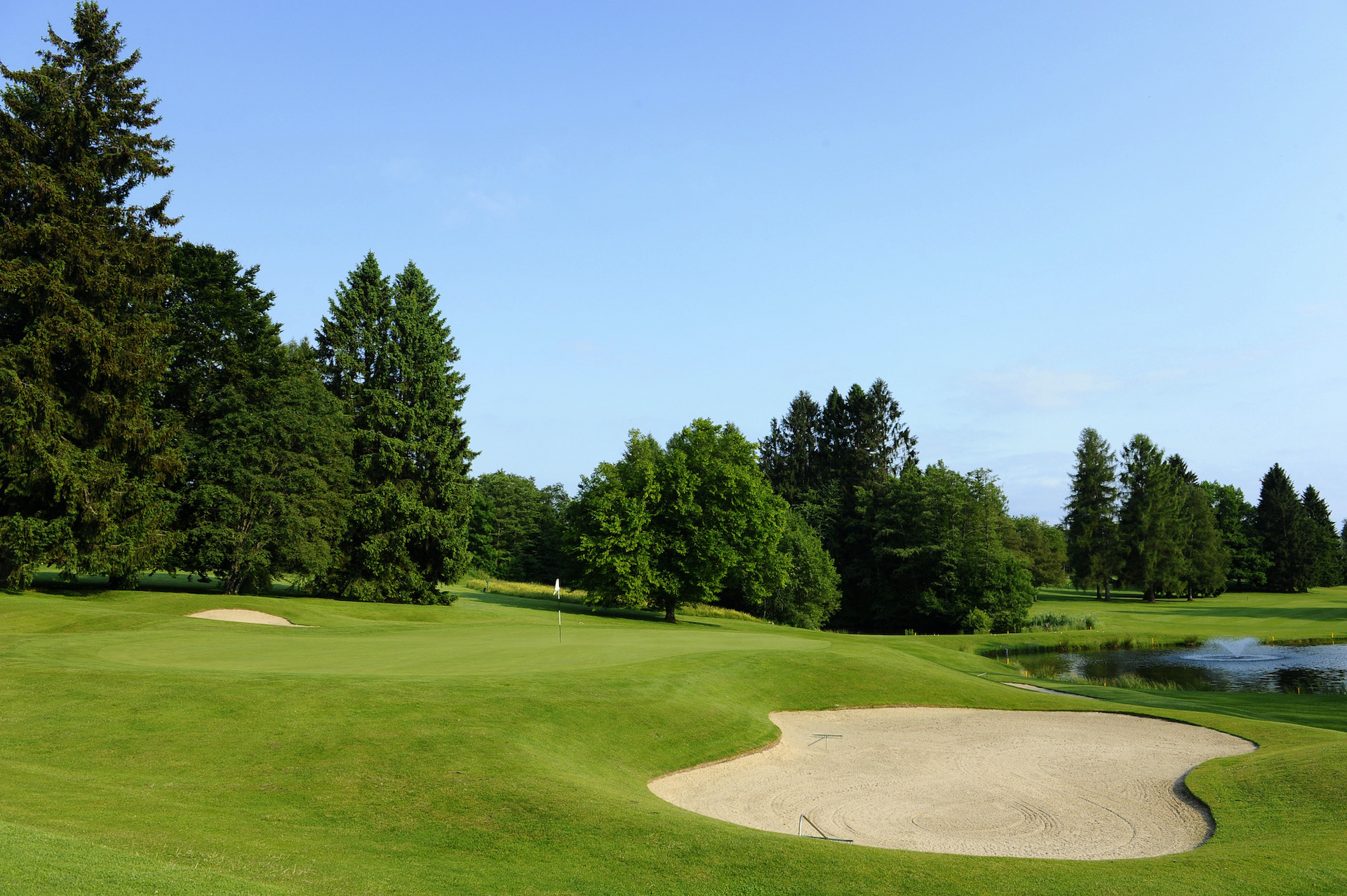 Tranquil golf course with lush greenery and a serene pond, embodying relaxation and focus for golf enthusiasts.