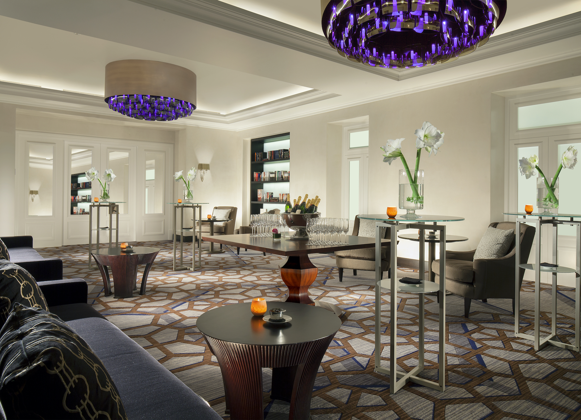 Spacious lounge with geometric carpet and striking purple chandelier, creating an elegant ambiance for hospitality settings.