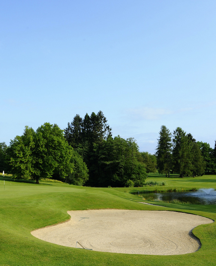 Vibrant golf course with lush greens and a serene pond, embodying tranquility and challenge for golf enthusiasts.