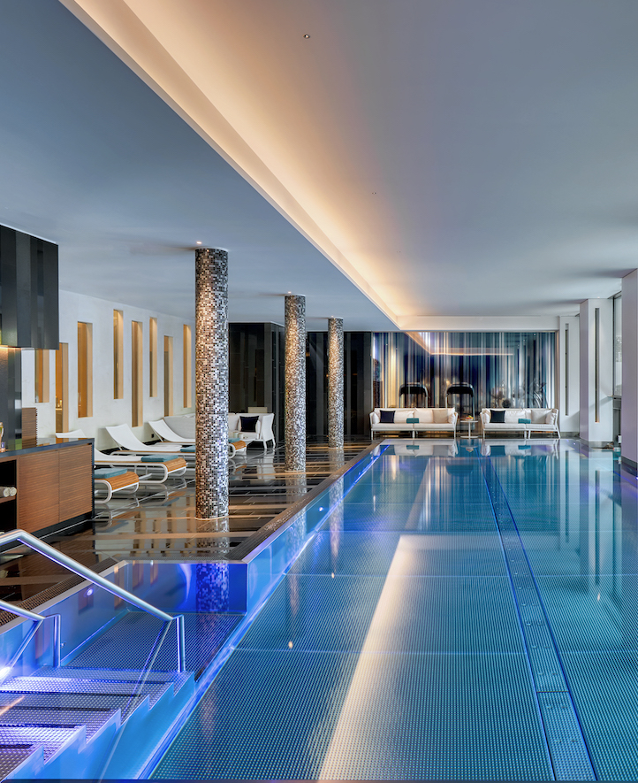 Sleek indoor pool with blue lighting and mosaic columns, creating a serene, luxury ambiance for relaxation and leisure in hospitality.