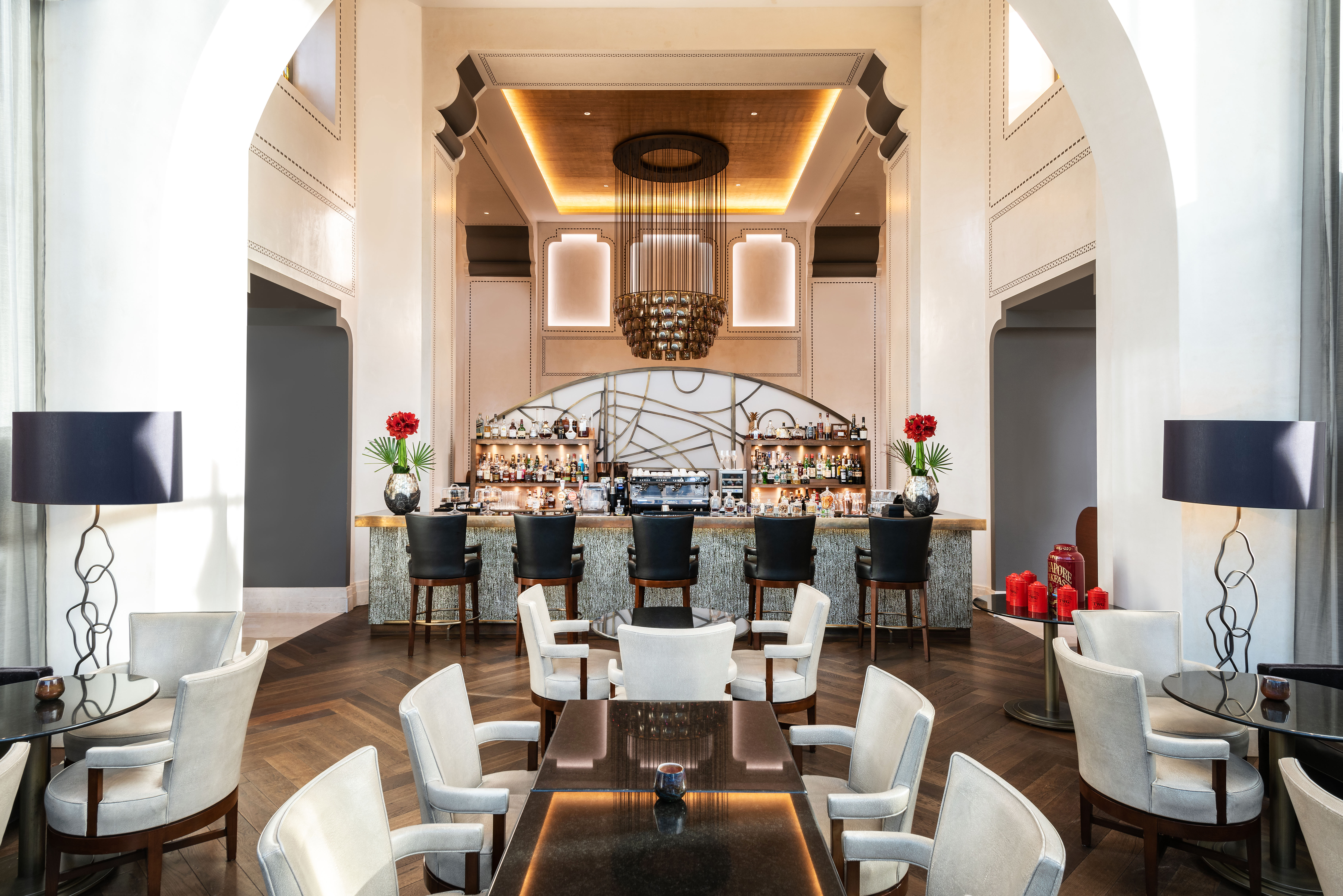 Elegant hotel bar with archways, gold accents, and a sophisticated chandelier, offering a welcoming, upscale ambiance for socializing.