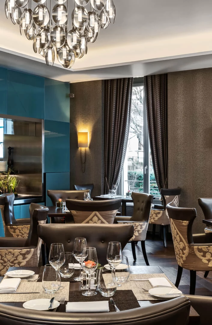 Elegant dining area with teal accents and modern chandeliers, evoking a sophisticated ambiance for diners.