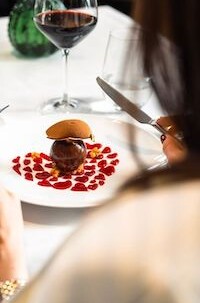 Elegant dining scene with a gourmet burger and red wine, arranged on a crisp white tablecloth—a romantic, upscale eating experience.